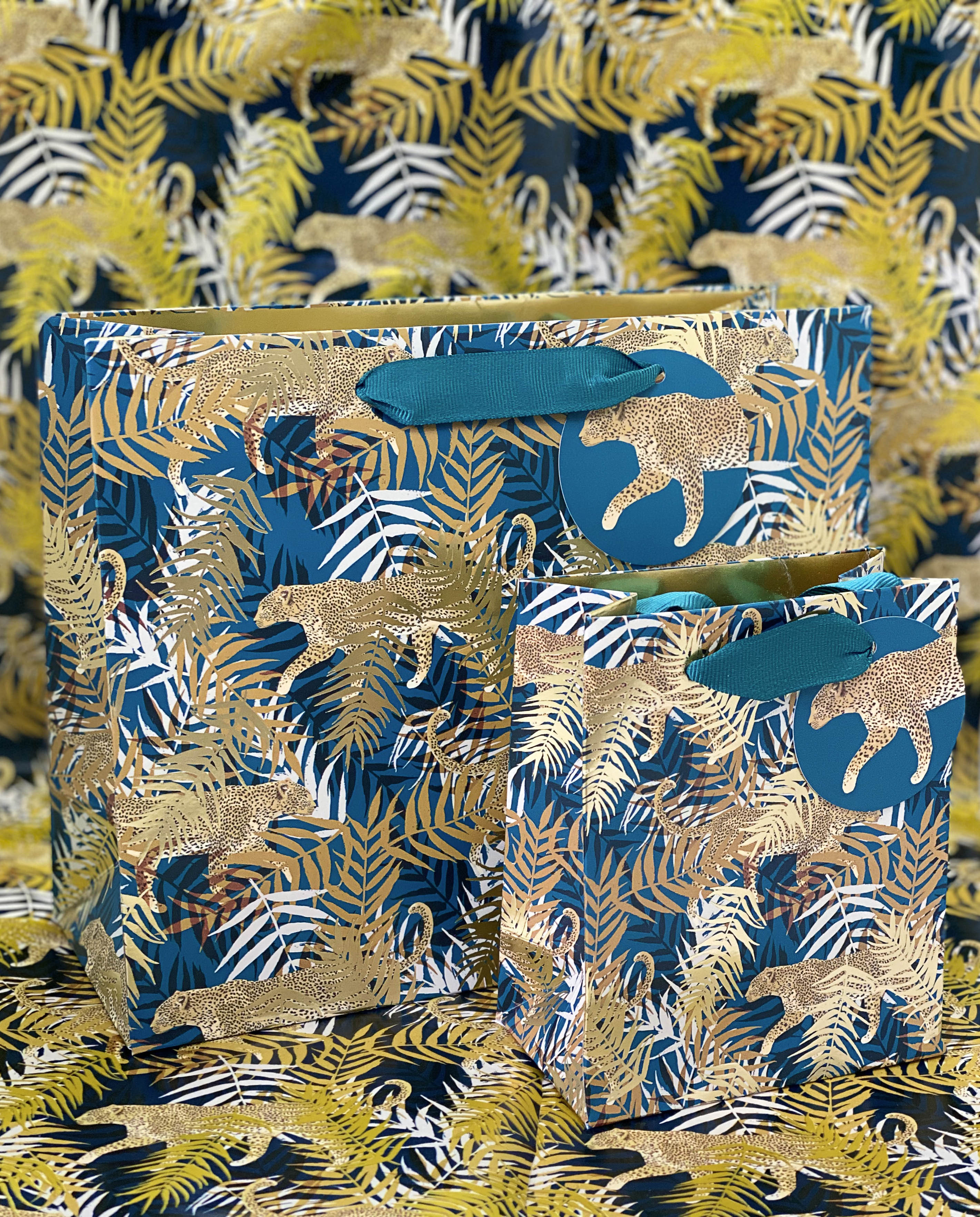 Leopard Gift Wrapping Image of gift bags with leopards and green adn gold leaves covering them. Background is the same pattern but in gift wrap.